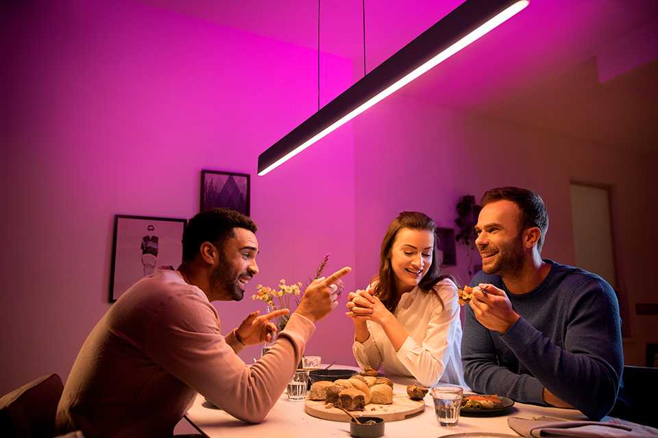 Friends having a snack at a breakfast table under a smart LED light.