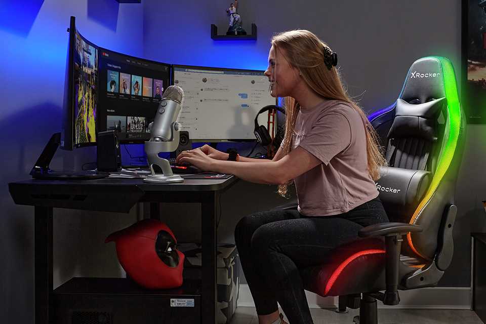 A girl playing video game sitting on X Rocker Alpha RGB Neo Motion LED eSports gaming chair.