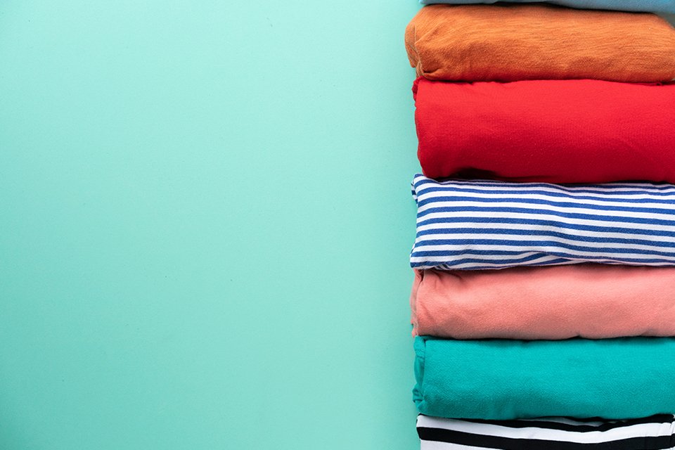  A close-up of rolled colorful clothes on green background.