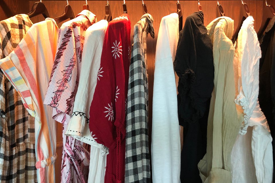 Close-up of women's clothes hanging in an illuminated wardrobe.