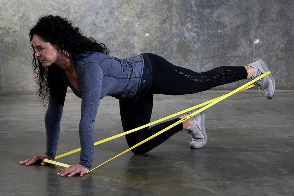 A woman using a TRX heavy strength band in yellow colour.