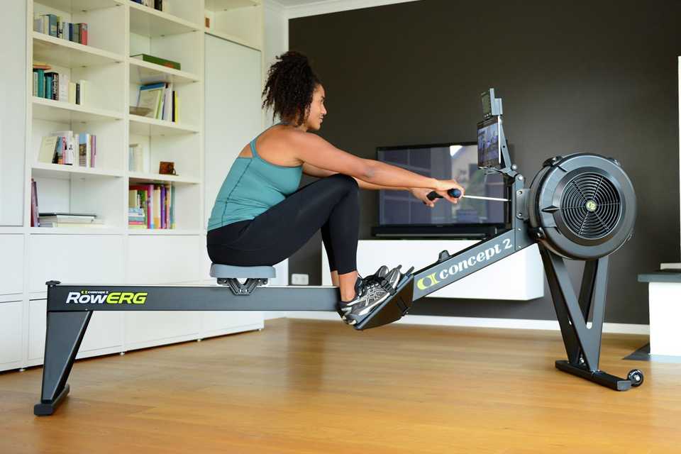 A woman using Concept2 RowErg with Tall Legs PM5 in black colour.