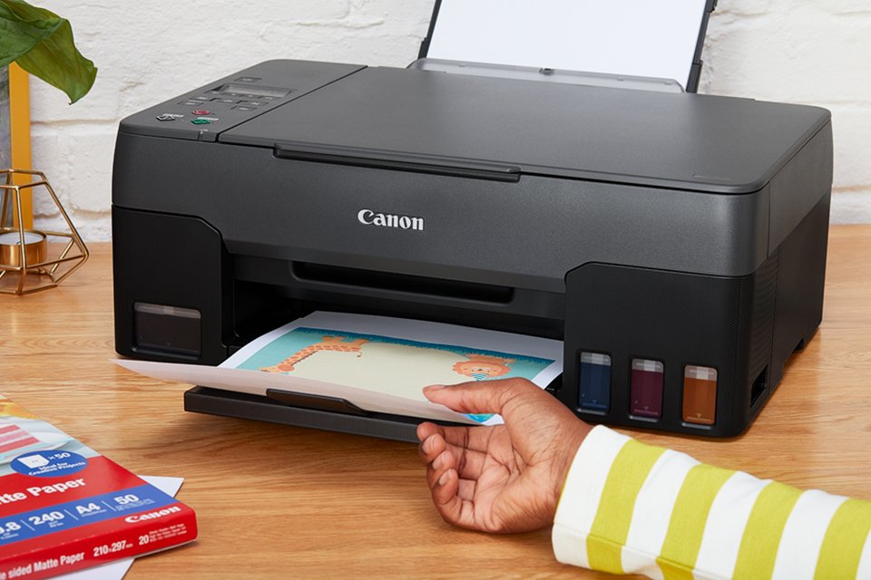 A person taking a printout using a Canon MegaTank printer. 
