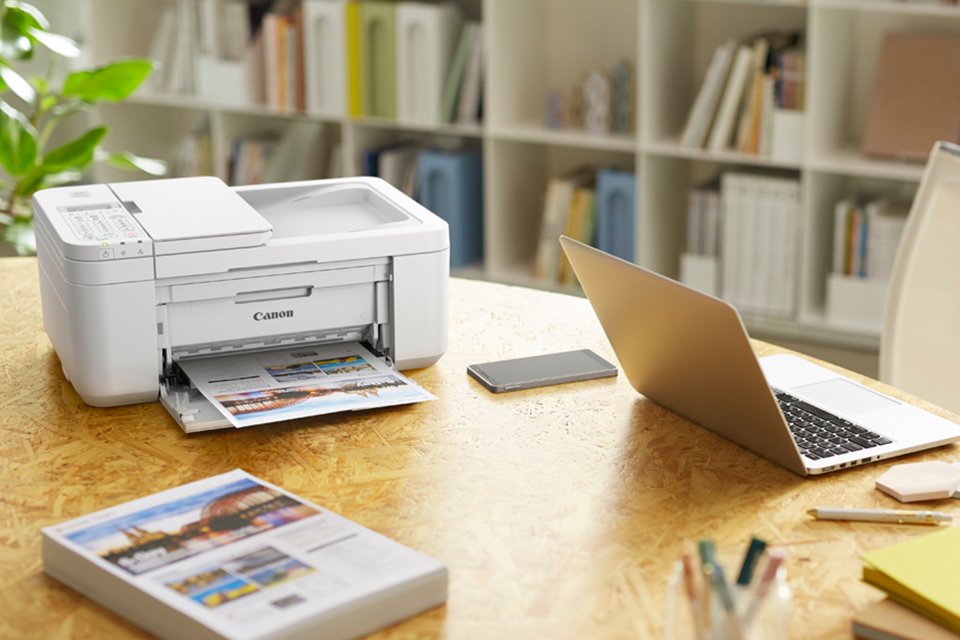 A Canon home office printer on a desk with other work-related essentials. 