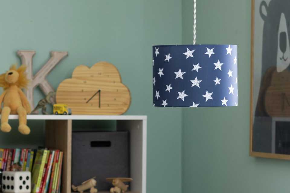 A ceiling light with blue and white star print lamp shade in a kid's room.