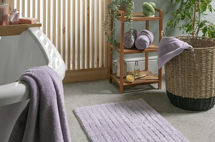 Bathroom with mustard towel and white and navy laundry basket.