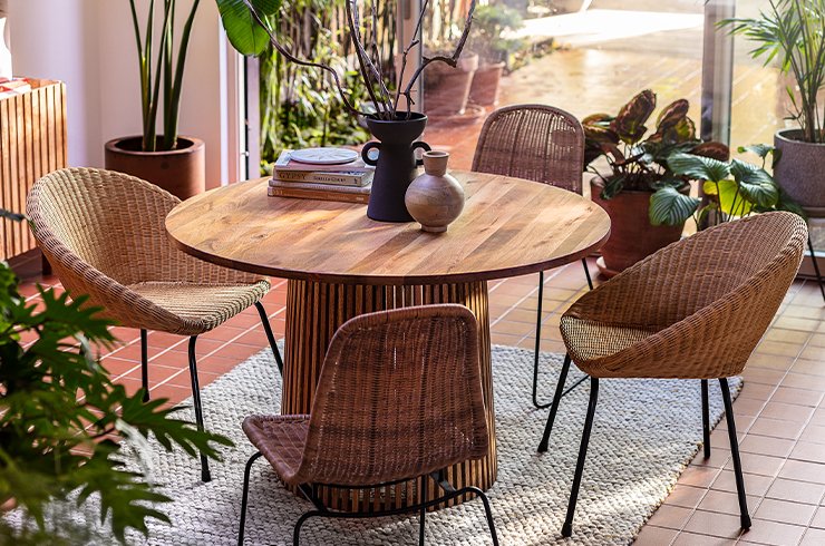 Oak dining room chairs around black circular dining room table and black hanging ceiling light.