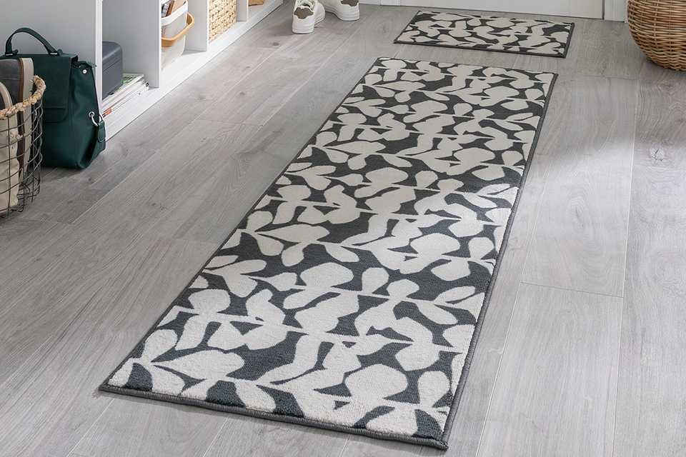 A monochrome, black and white runner and welcome mat in a hallway.