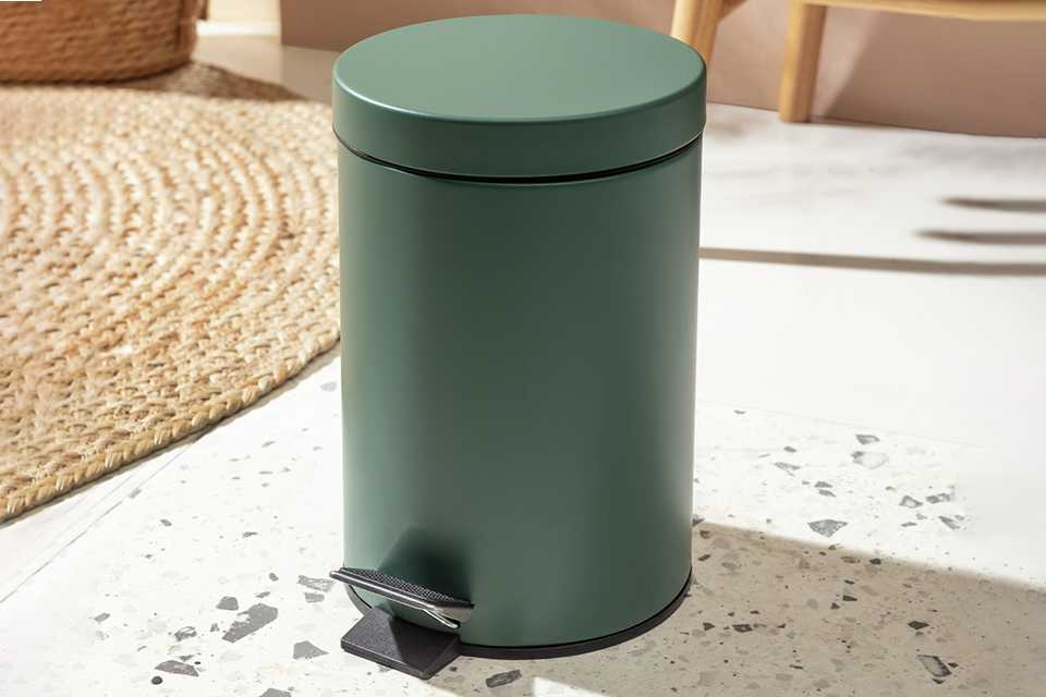 A dark green recycling bin sitting on a floor.