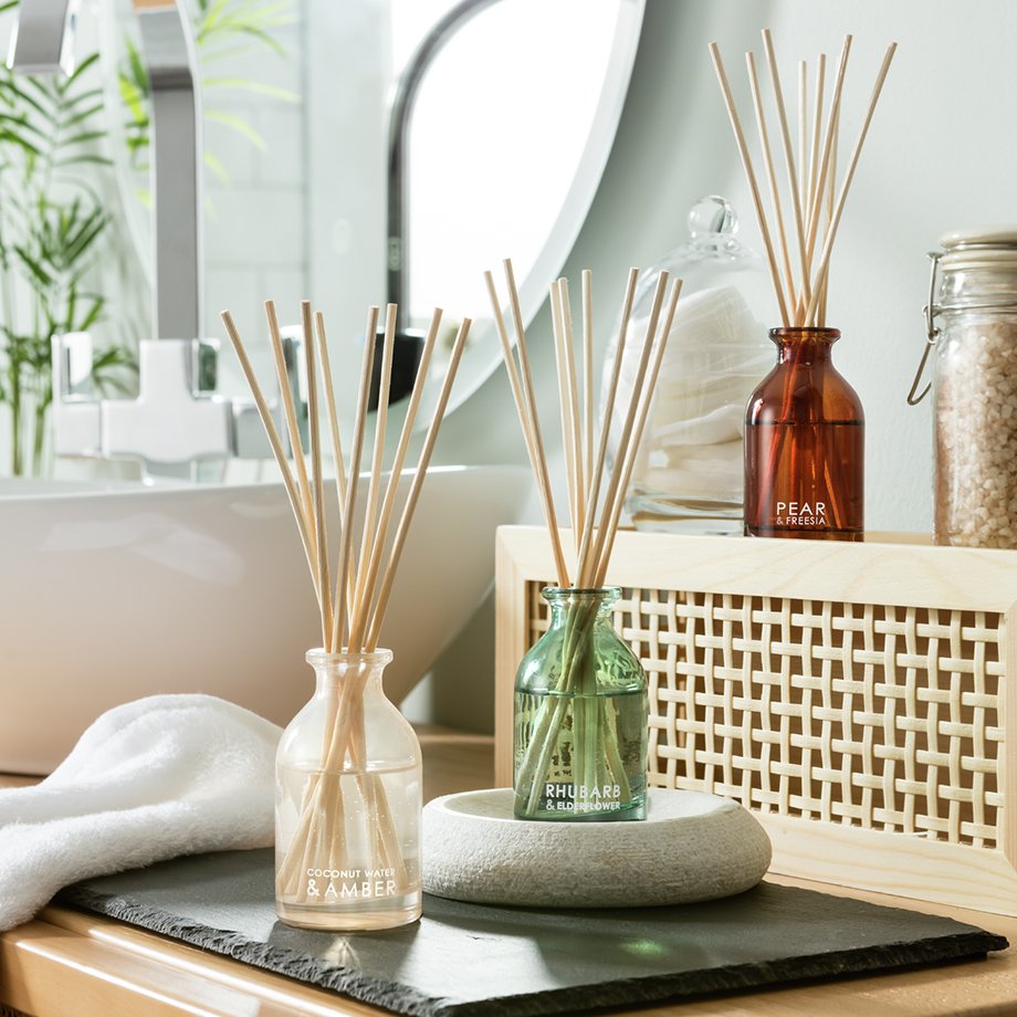 A Habitat two-tone bamboo ladder with mirror shelving unit placed in a bathroom next to a woven wicker laundry basket.