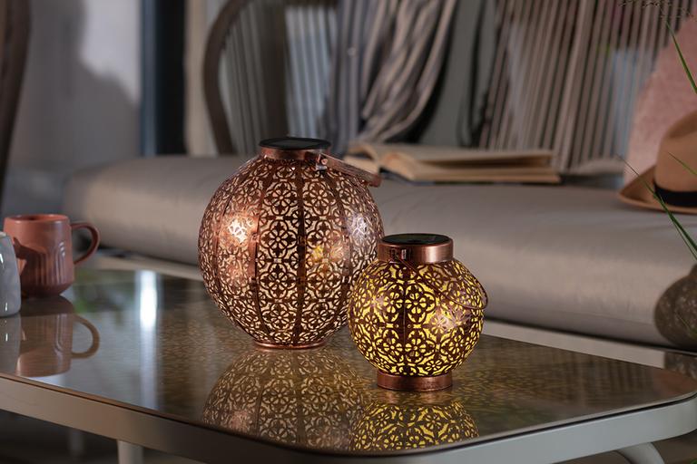 A pair of Habitat solar lanterns in bronze placed on a coffee table.