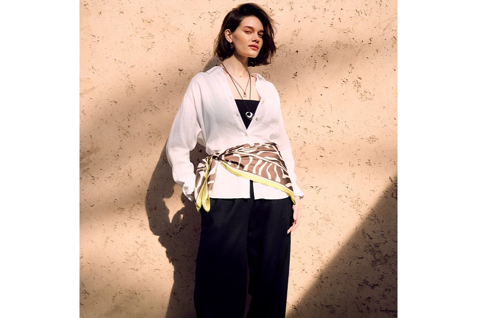 Light yellow short‑sleeve button‑front midi dress styled with a brown knit layered over the shoulders on a clean studio background.