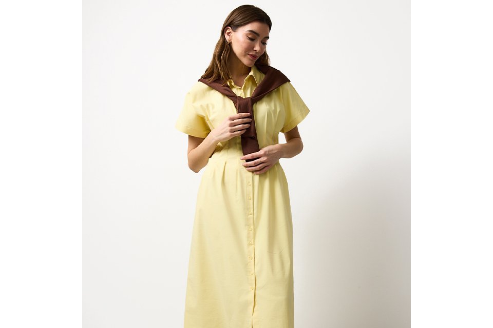 White lightweight button‑through shirt styled with black wide‑leg trousers and a brown patterned scarf tied at the waist in an outdoor setting.