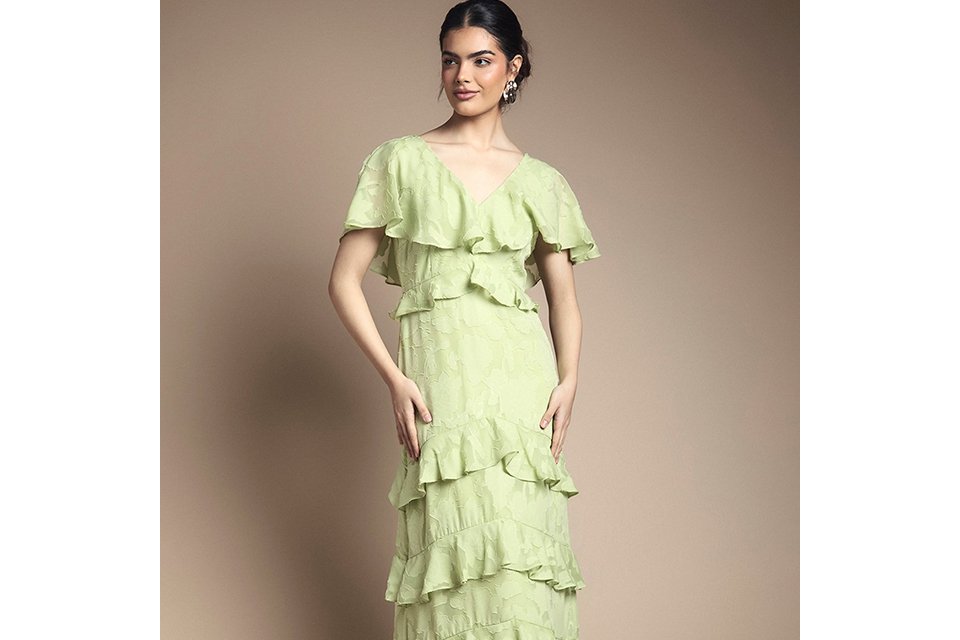 Light green ruffle tiered midi dress with short flutter sleeves and V‑neck, styled with white strappy sandals on a neutral background.