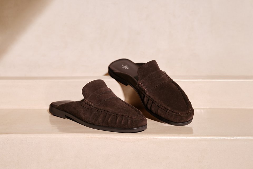 A cut out image of brown flat slip on loafers. 