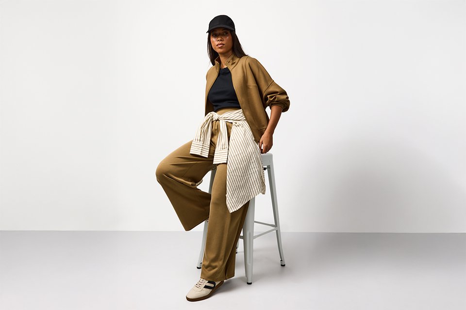 Neutral spring outfit featuring tailored trousers, a soft knit top and lightweight layers, styled for an effortless capsule wardrobe. 