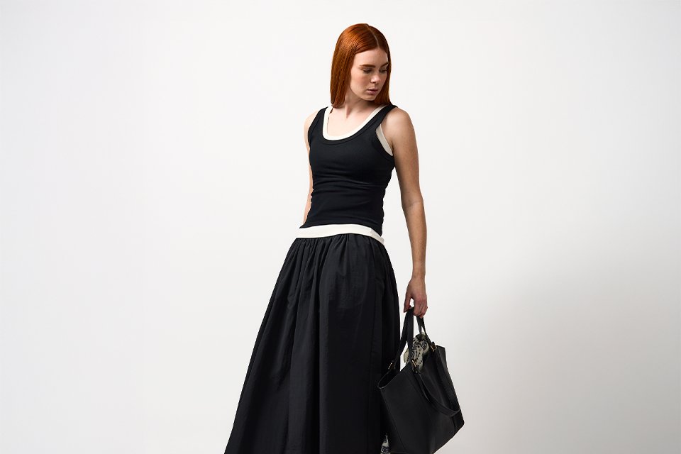 Black midi dress styled with minimal accessories, showcasing a versatile spring outfit with a clean, modern silhouette.