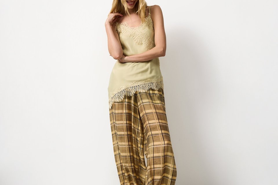 Light summer outfit featuring a sleeveless top paired with neutral trousers, showcasing an effortless warm‑weather look. 