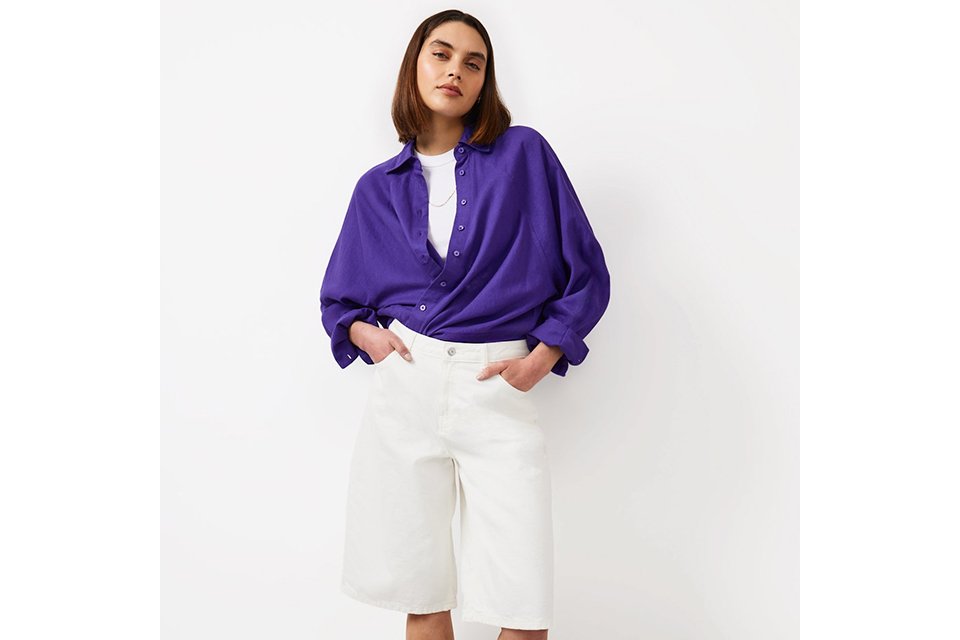 Model wearing a bright purple knit jumper styled with white trousers for fresh spring outfits.