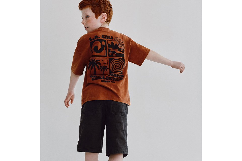Graphic short sleeve T‑shirt paired with knee‑length shorts, styled for boys’ new‑in casual outfits. 