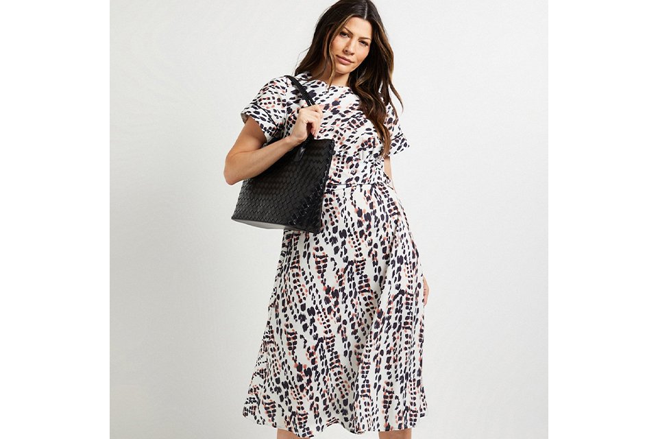 Model wearing a black and white printed midi dress styled for spring occasions and wedding season.