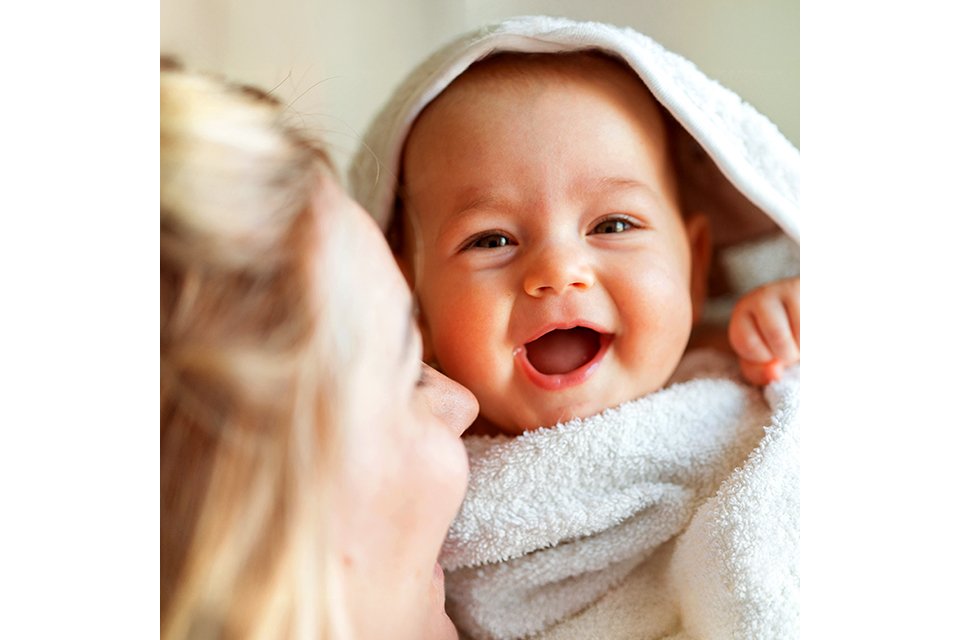 A baby wrapped in a towel being held by a woman.