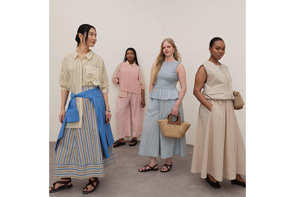 A women wearing white linen trousers and white top with a longline burgundy shirt.