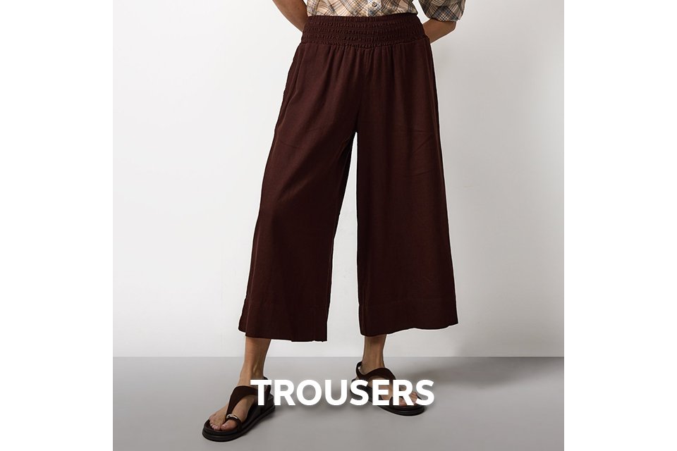 Woman wearing brown wide leg cropped trousers and a check shirt.