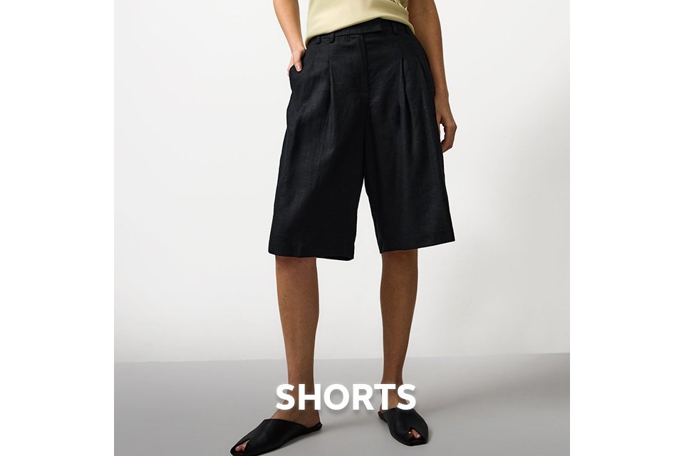 Woman wearing long black shorts with a butter yellow cami top.