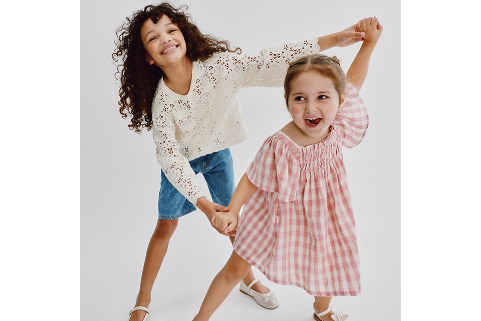 Person dressed in a thick, light brown and cream faux fur coat layered over a dark textured top, shown from the waist up.