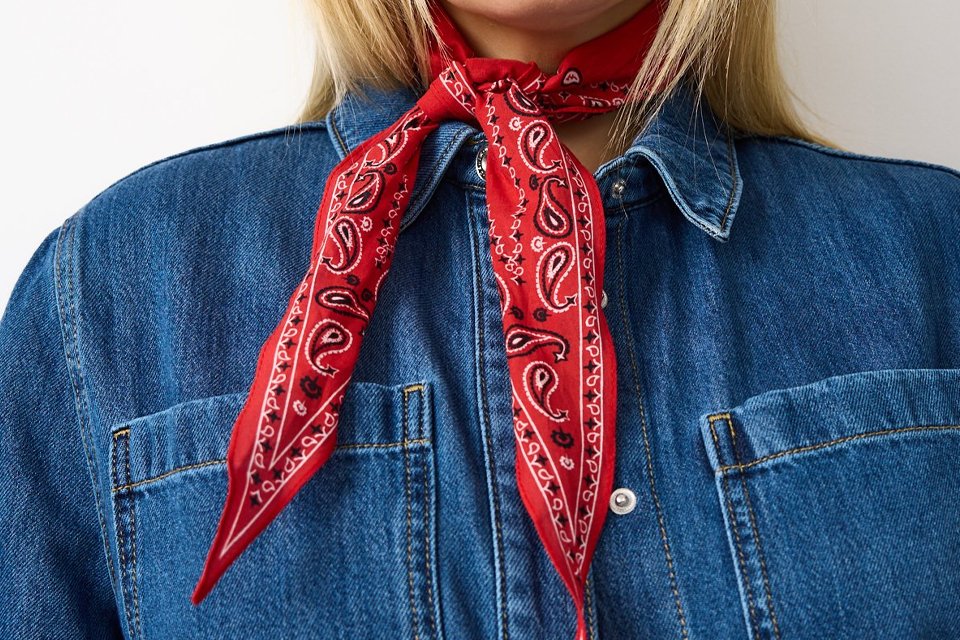Denim jacket styled with a red patterned scarf, showing festival accessories for layered summer looks.