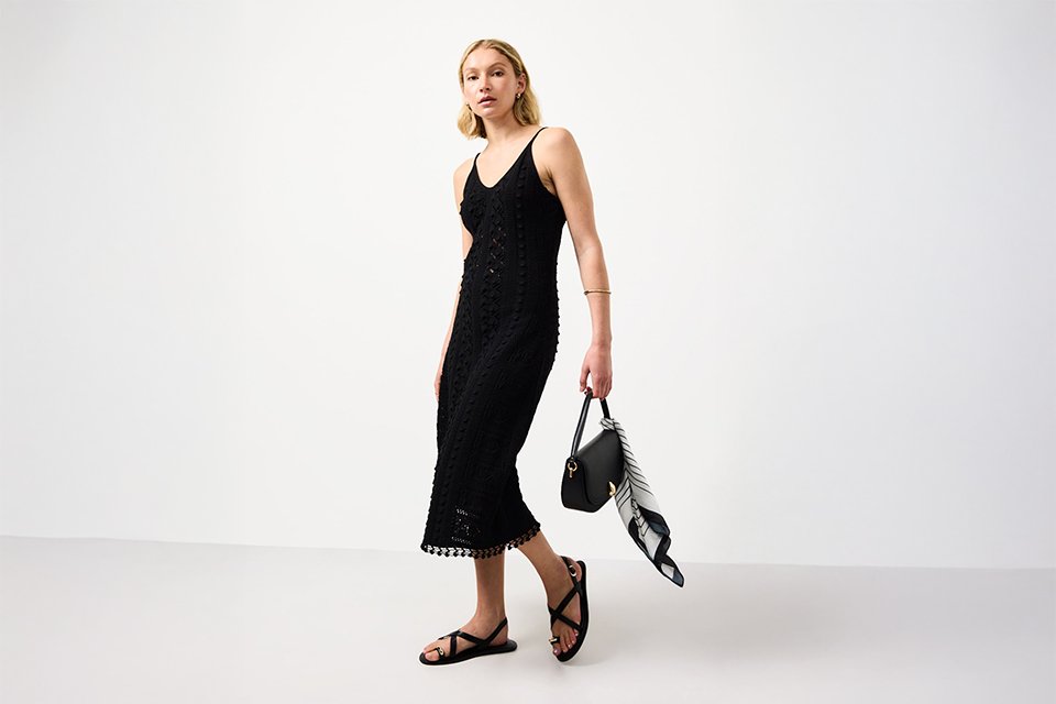 Black festival dress styled with sandals and small shoulder bag for a relaxed day-to-night festival outfit.