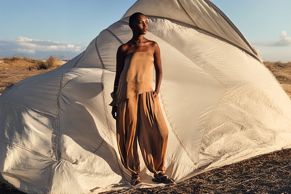 Neutral sleeveless top with relaxed trousers styled with lightweight layers for a modern summer outfit.
