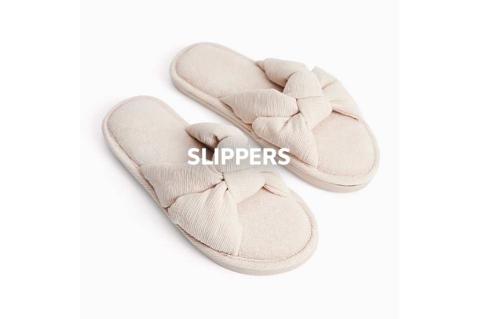Beige women’s slippers with bow detail – cosy soft indoor footwear.
