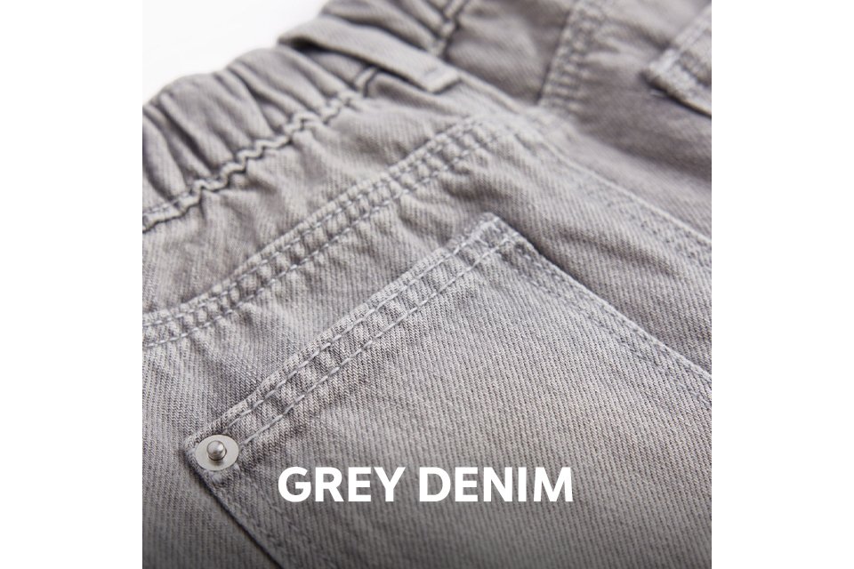 Close-up of the back of light grey denim jeans featuring an elasticated waistband, belt loops, and a back pocket with rivet detailing.