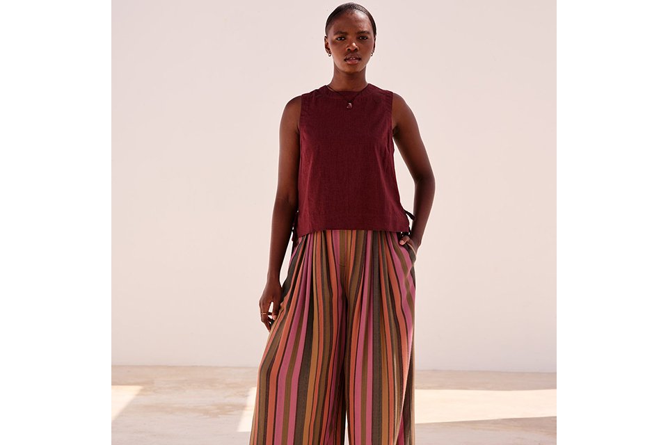 Burgundy sleeveless top styled with striped wide-leg trousers for summer outfit inspiration.