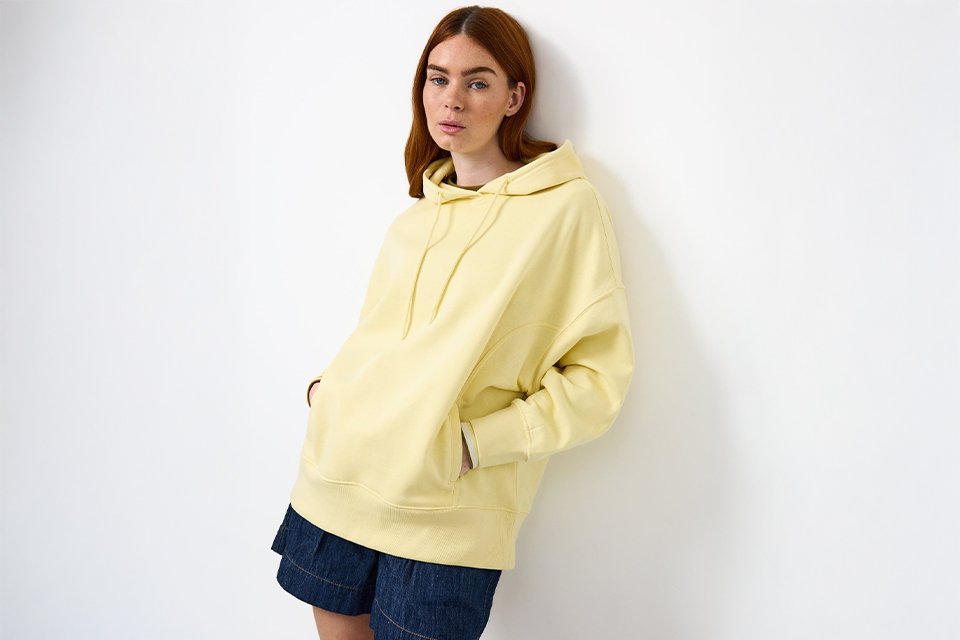 Yellow hoodie styled with denim skirt for casual UK staycation packing outfit.