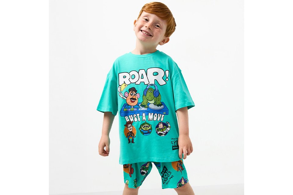 Graphic short sleeve T‑shirt paired with knee‑length shorts, styled for boys’ new‑in casual outfits. 