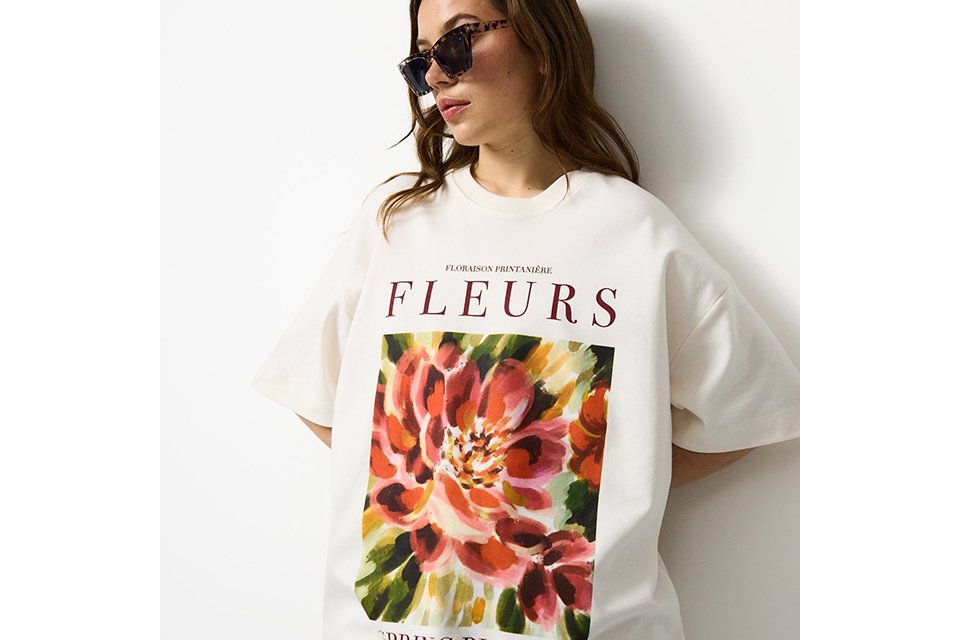 Oversized white graphic T-shirt styled as a relaxed festival outfit for summer events and music festivals.