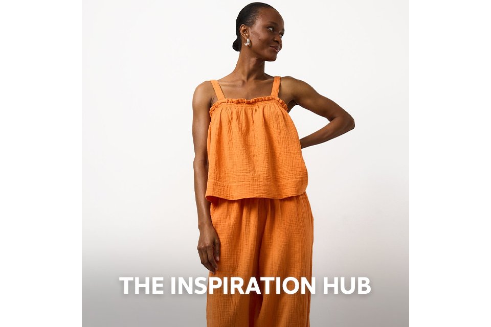 Woman wearing double cloth orange co ord, with orange wide leg trousers and orange cami top.