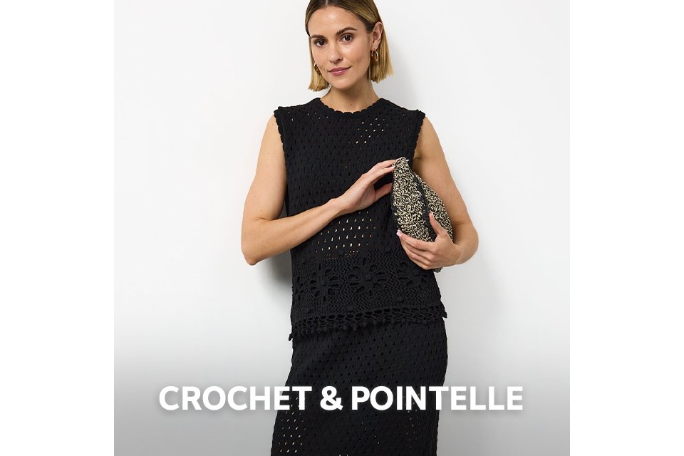 Woman wearing black crochet co ord, carrying a woven bag and wearing black flat sandals.
