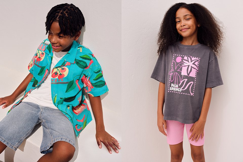 A picture showing two children, one with a girl wearing pink cycling shorts and a grey top, and another with a boy wearing a bright shirt, white tee and denim shorts.