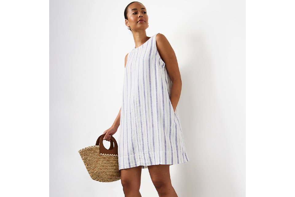 Woman wearing white linen mini dress with blue stripes.