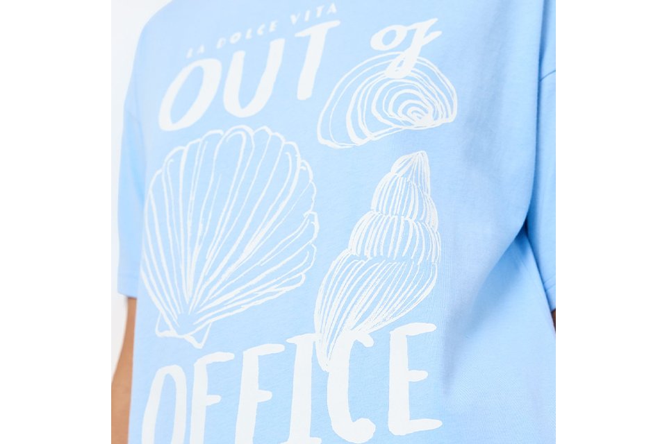 Light blue graphic T-shirt featuring white seashell illustrations and "Out of Office Amalfi Summer" slogan print.