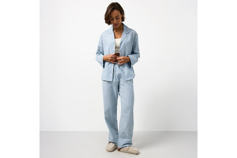 Blue and white striped pyjama set featuring a long-sleeve button-through shirt and matching wide-leg trousers.