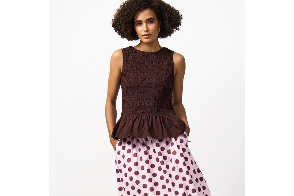 A woman wearing a polka dot skirt, paired with a brown sleeveless top.