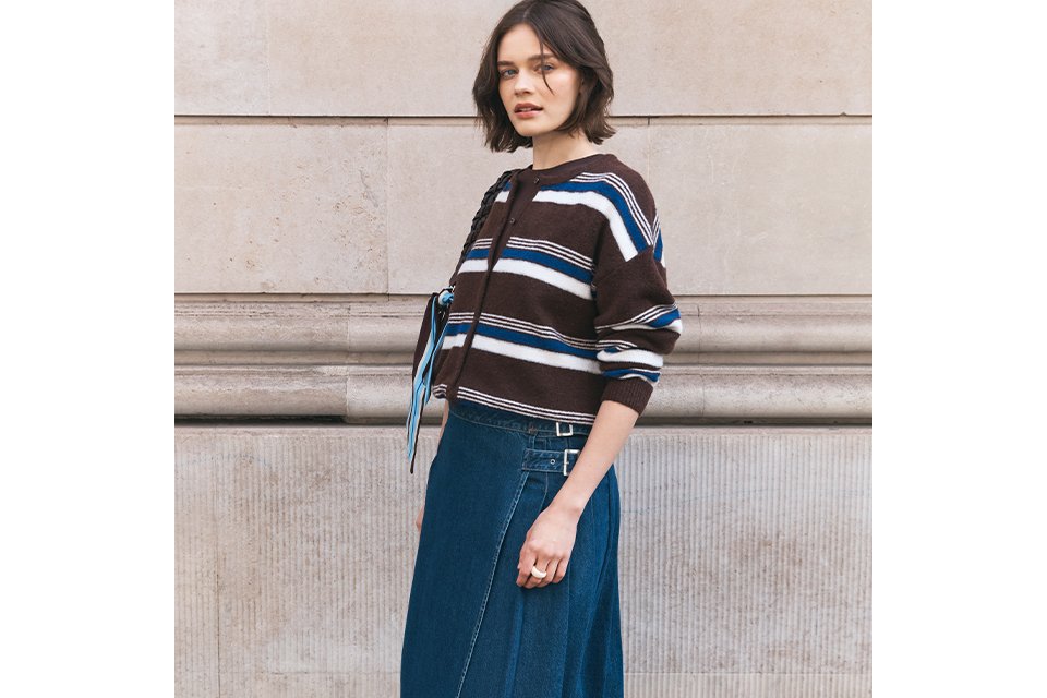 Woman wearing maxi denim skirt, with white ballet flats, and a stripey top.