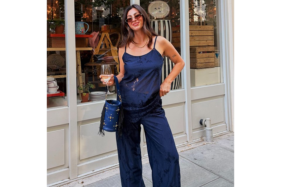 A woman wearing a navy cami top and navy wide-leg trousers.