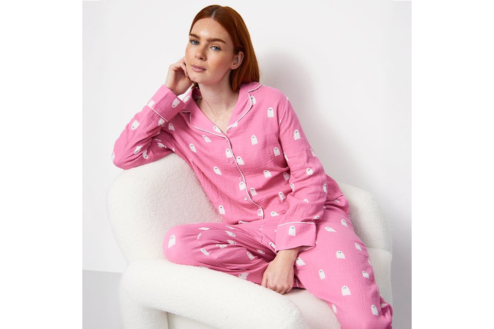 A woman wearing pink pyjamas with white ghosts on them.
