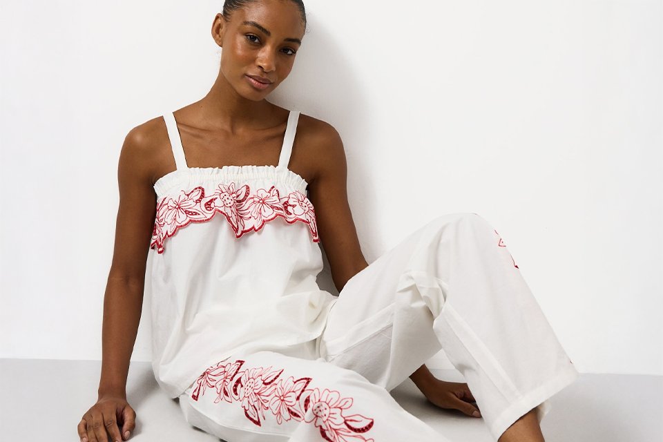 White embroidered co-ord set featuring a strappy camisole top and wide-leg trousers with red floral embroidery detailing and a relaxed fit.